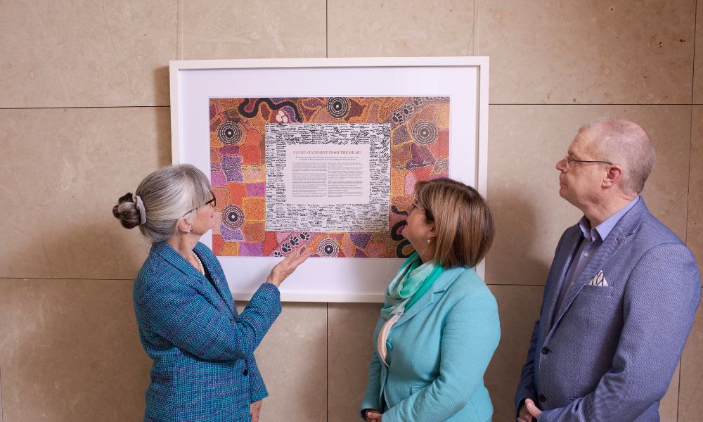 Gabi Hollows, Jane Madden and Ian Wishart looking at a frame on the wall of The Uluru Statement of The Heart