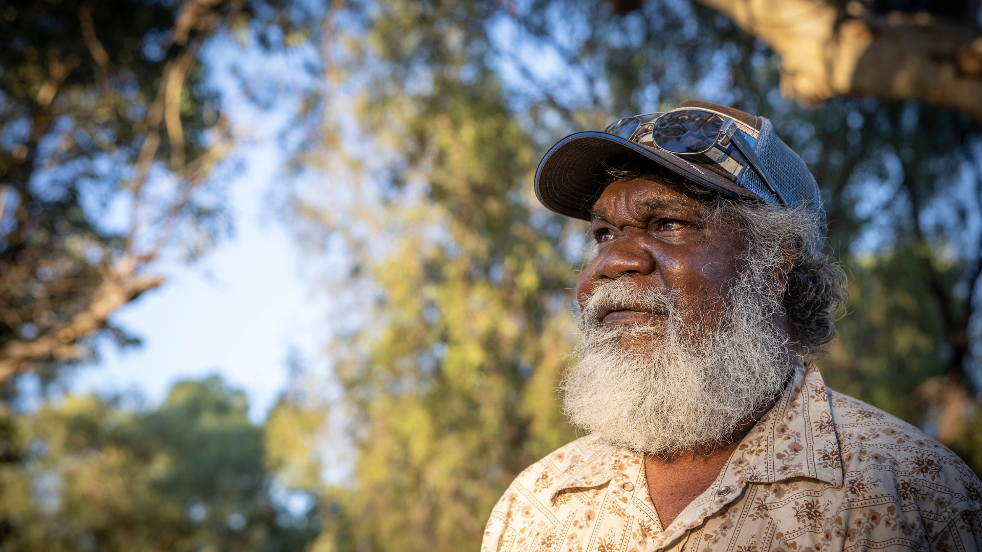 Jeffrey Foster in Alice Springs, looking off into the distance with trees in the background