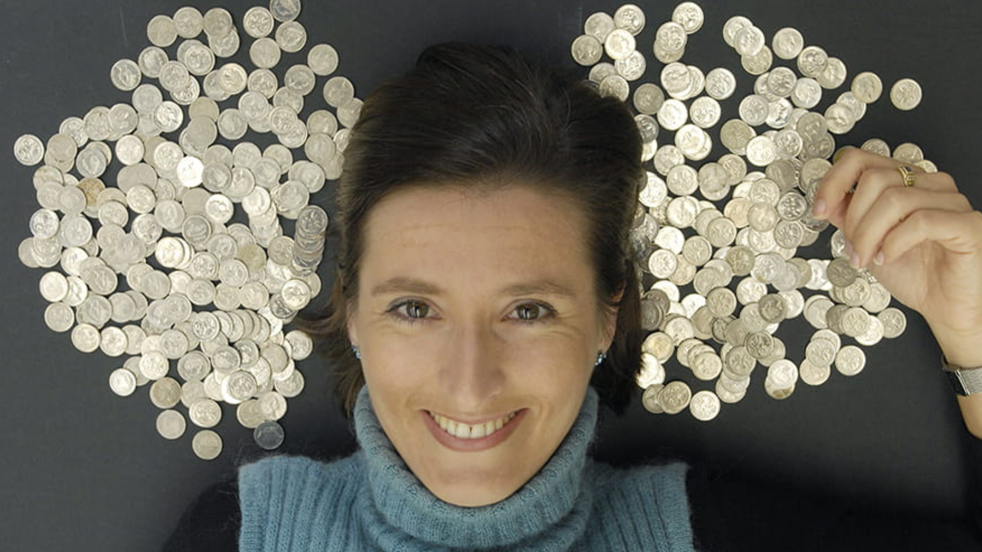 A woman lying down with silver coins side by side