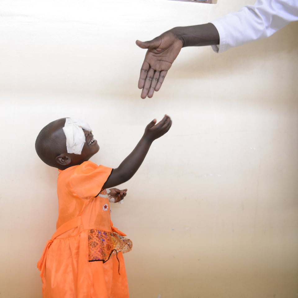 Small child reaching up to shake hands with a doctor