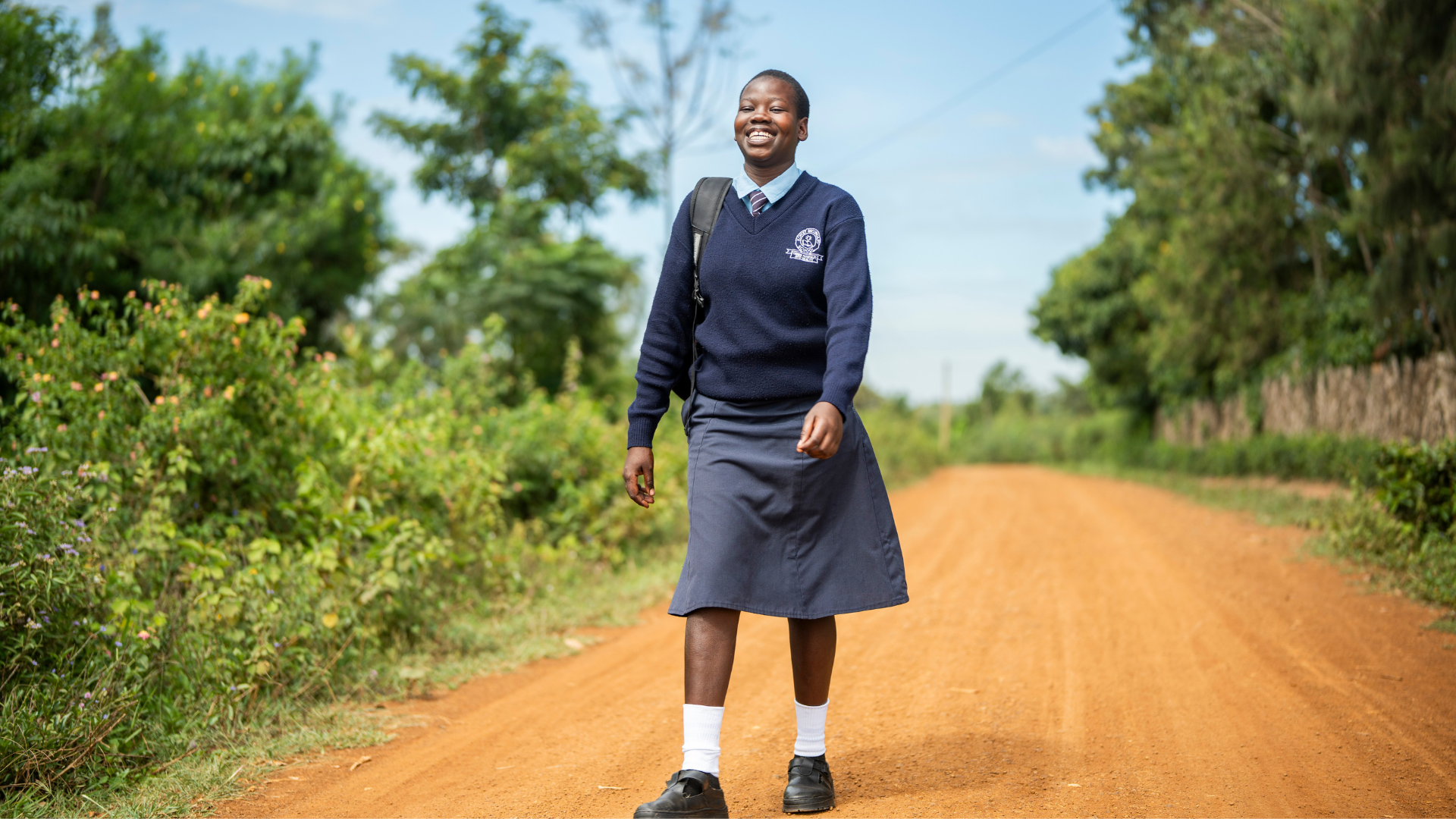 Mitchel in her school uniform walking to school up a dirt road