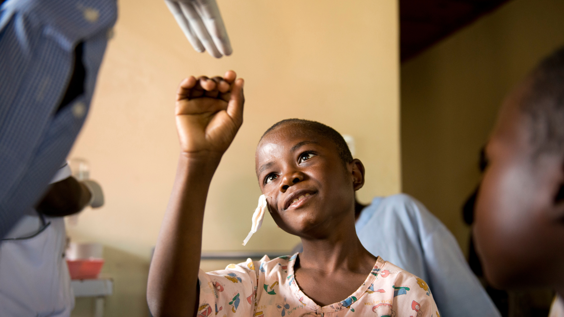 Collins from Kenya reaching his hand out to a medical professional, just after having his patch removed.