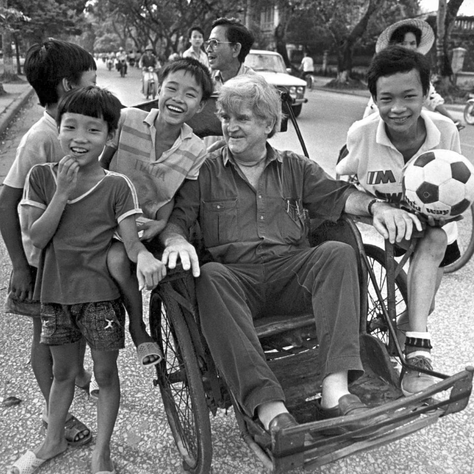 Black and white image of Fred playing with local children in Vietnam