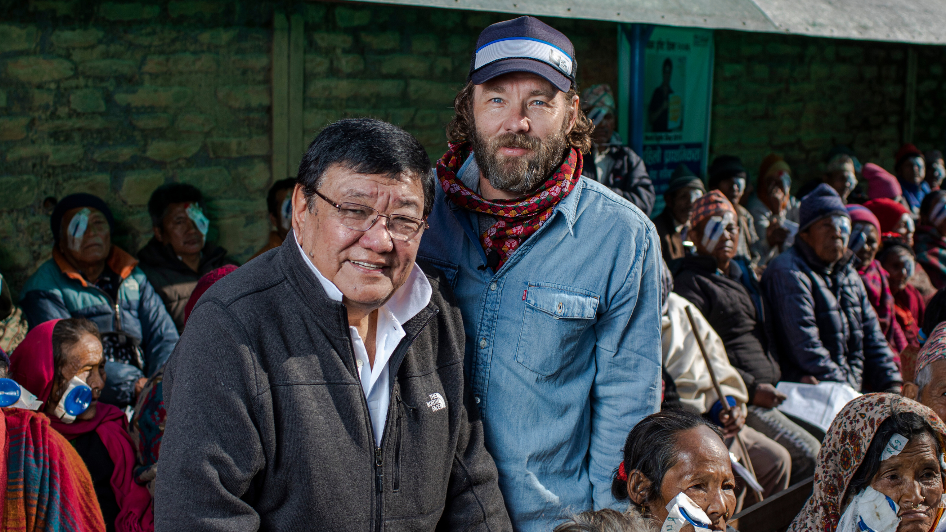 Dr Ruit and Fred Hollows Foundation ambassador Joel Edgerton at an eye camp in Nepal with patients