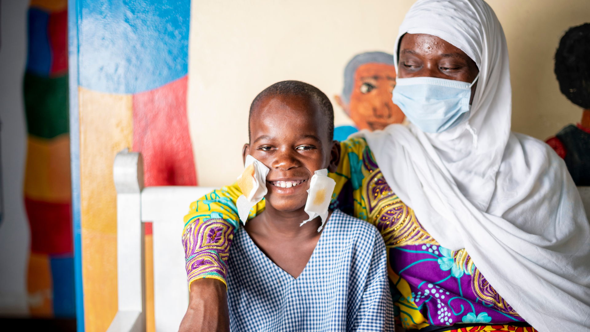 Mwajungu with her arm around her son, Mbaruku, after his eye patch is removed 