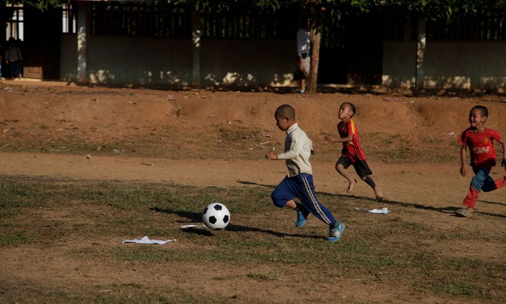 Hao kicking a football with friends two years after his successful cataract operation supported by The Fred Hollows Foundation. 