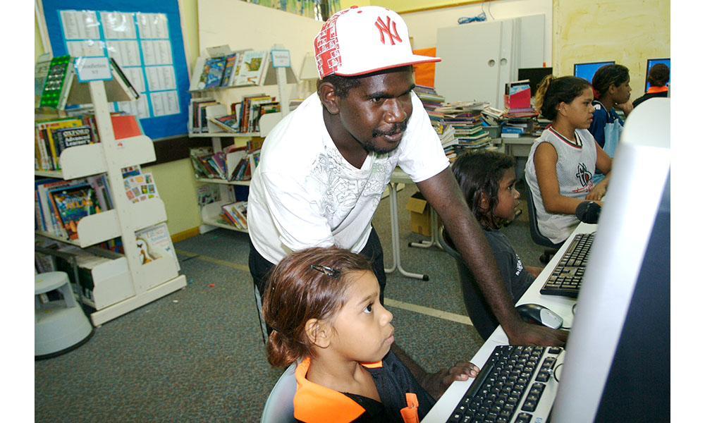 Man looking over students shoulder at computer