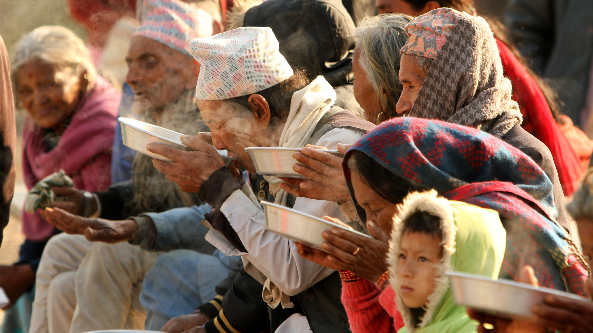 People in Nepal sitting down and eating food out of a bowl