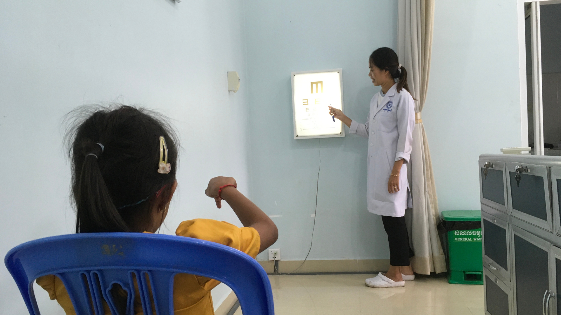 Sreyleap looking at a board with letters on it to test her eye sight