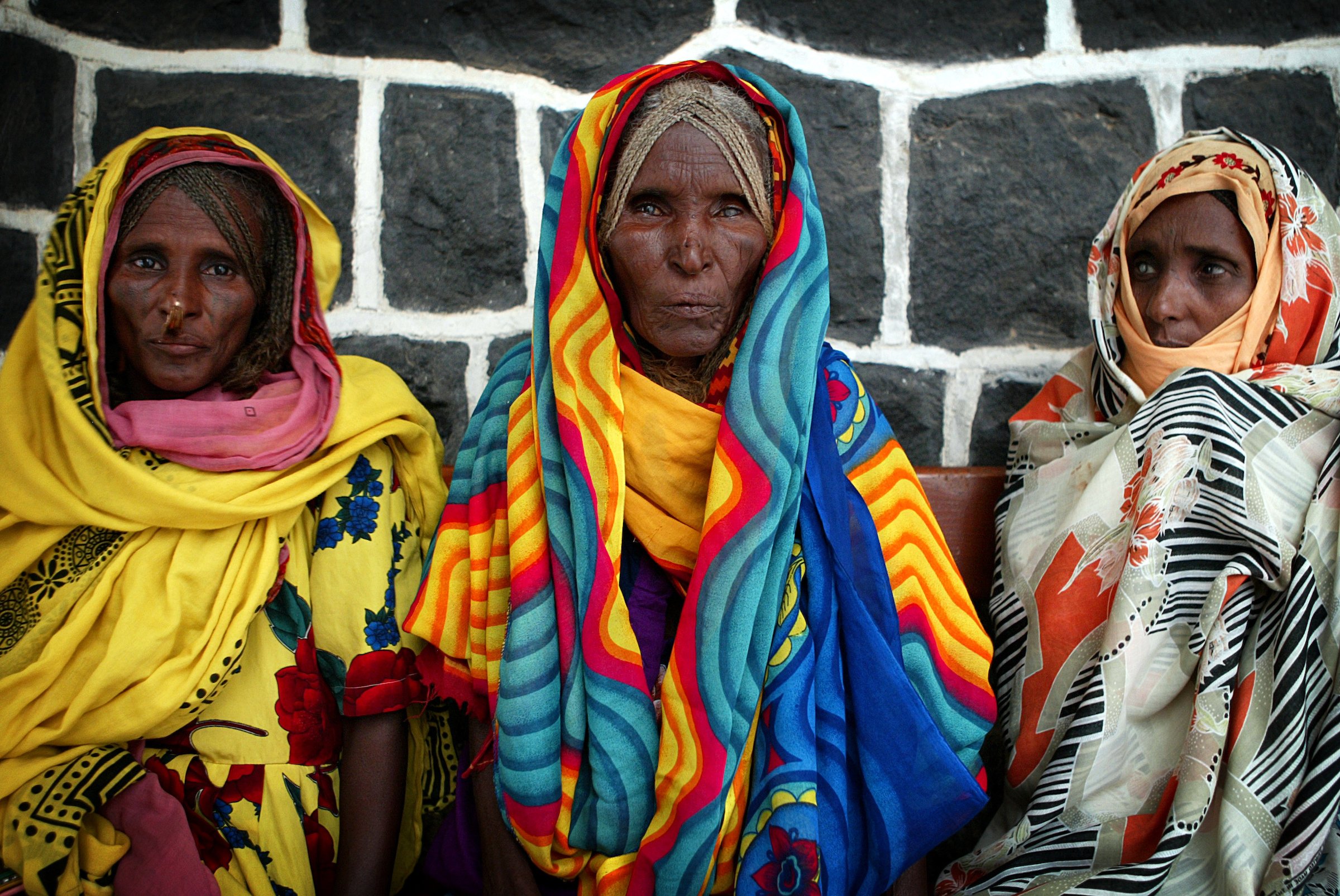 Three women in colourful robes await cataract surgery.