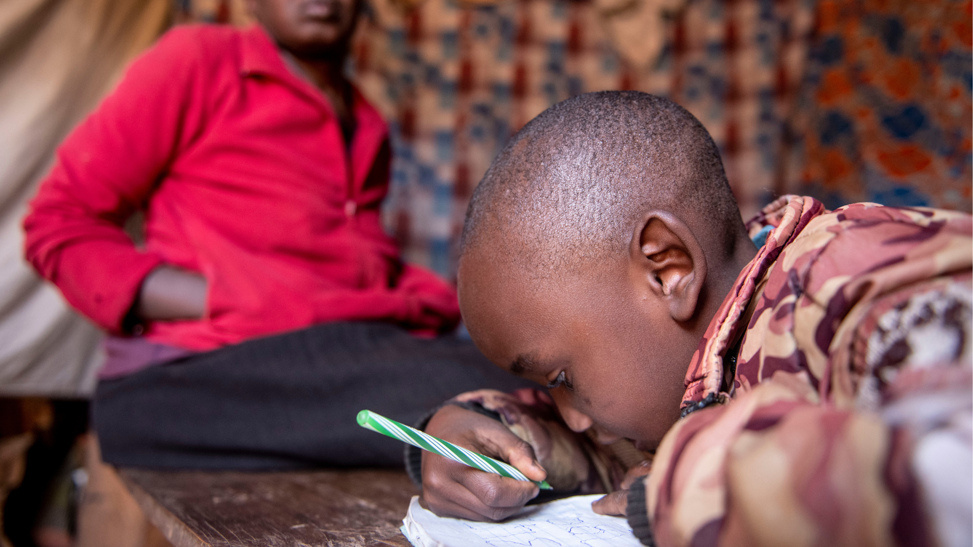 mbugua writing in a notepad pressing their face close to see what they are writing 