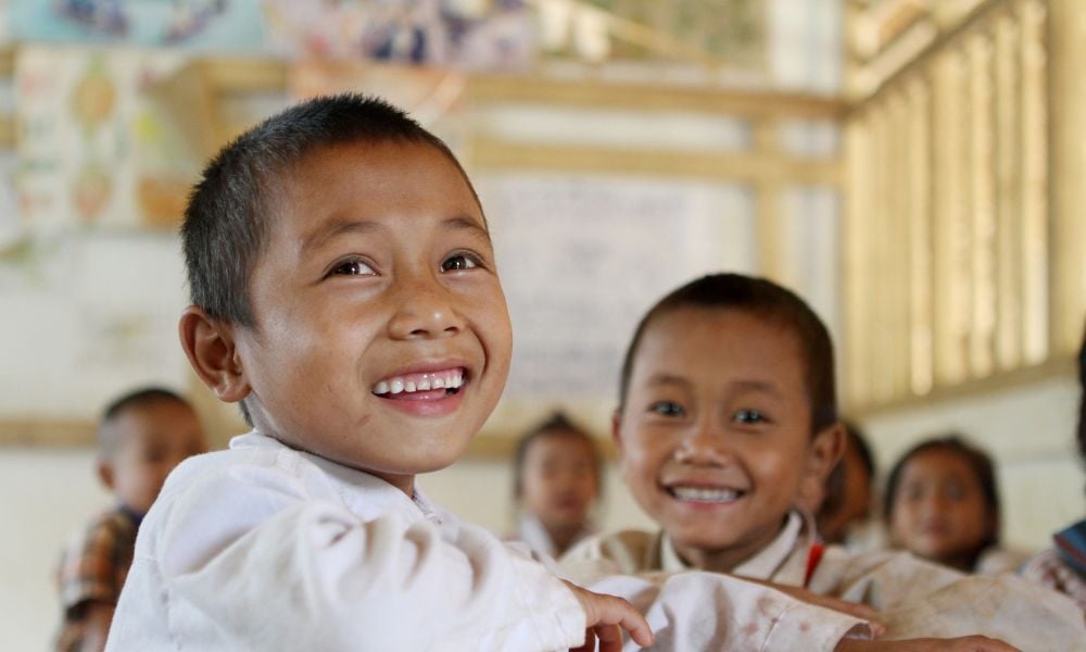 Child at his desk smiling at the camera person 