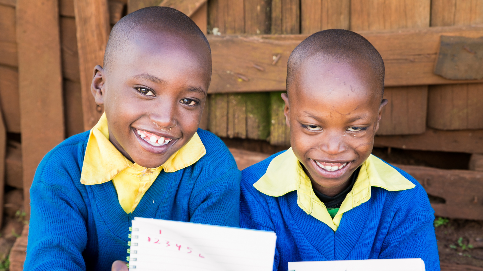 Samuel from Kenya (right) sitting with his brother showing their drawings