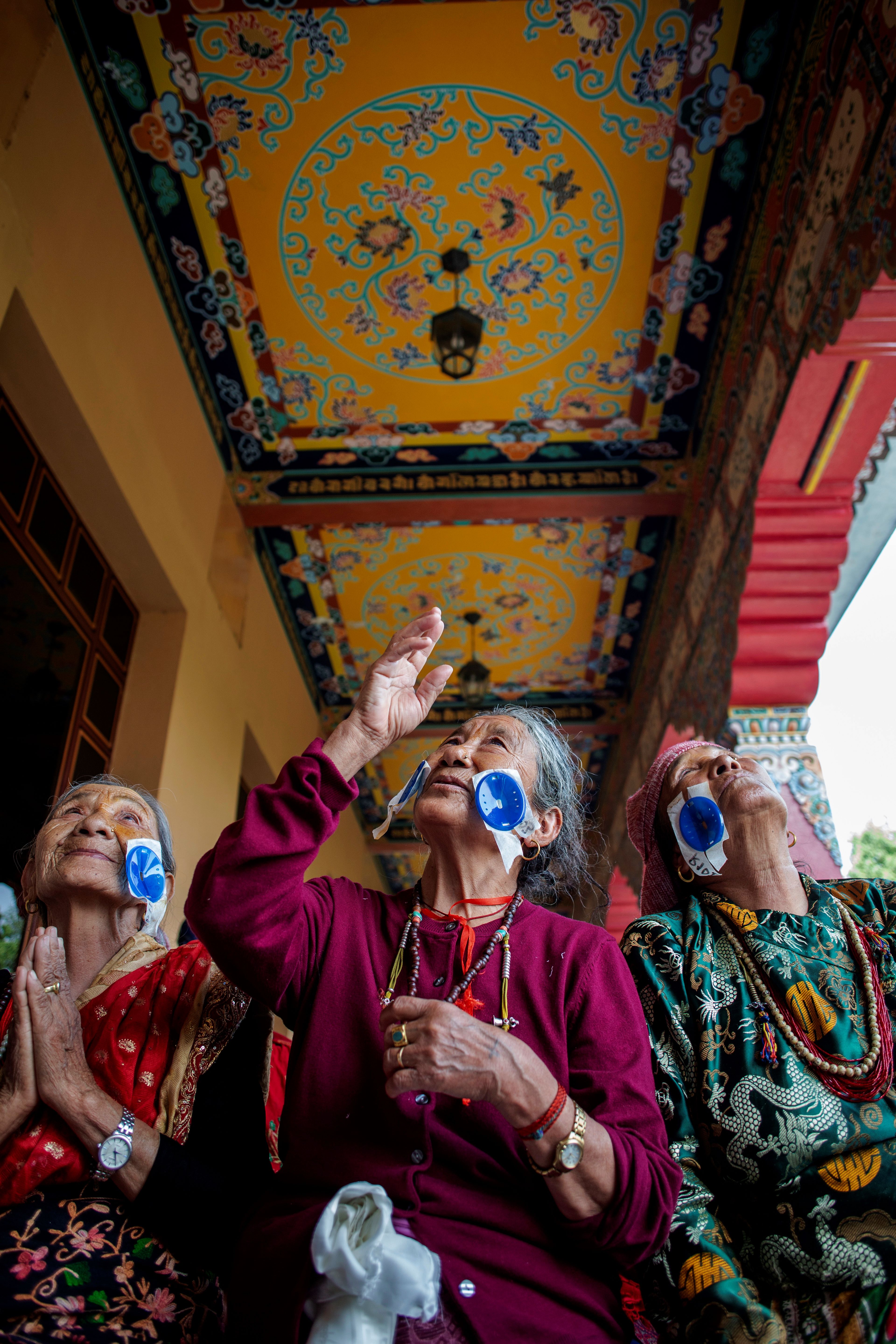 Chini Lama, 74, gazes up at the Buddhist mural paintings above her the morning after her cataract surgery and just following her post-operative examination. Chini, who is bilaterally blind, was accompanied by her friend Tashi Dolma, 70 (in a green dress), and Suna Lama, 80 (wearing glasses) on either side; both had surgery on the same day. Picture taken by Michael Amendolia.